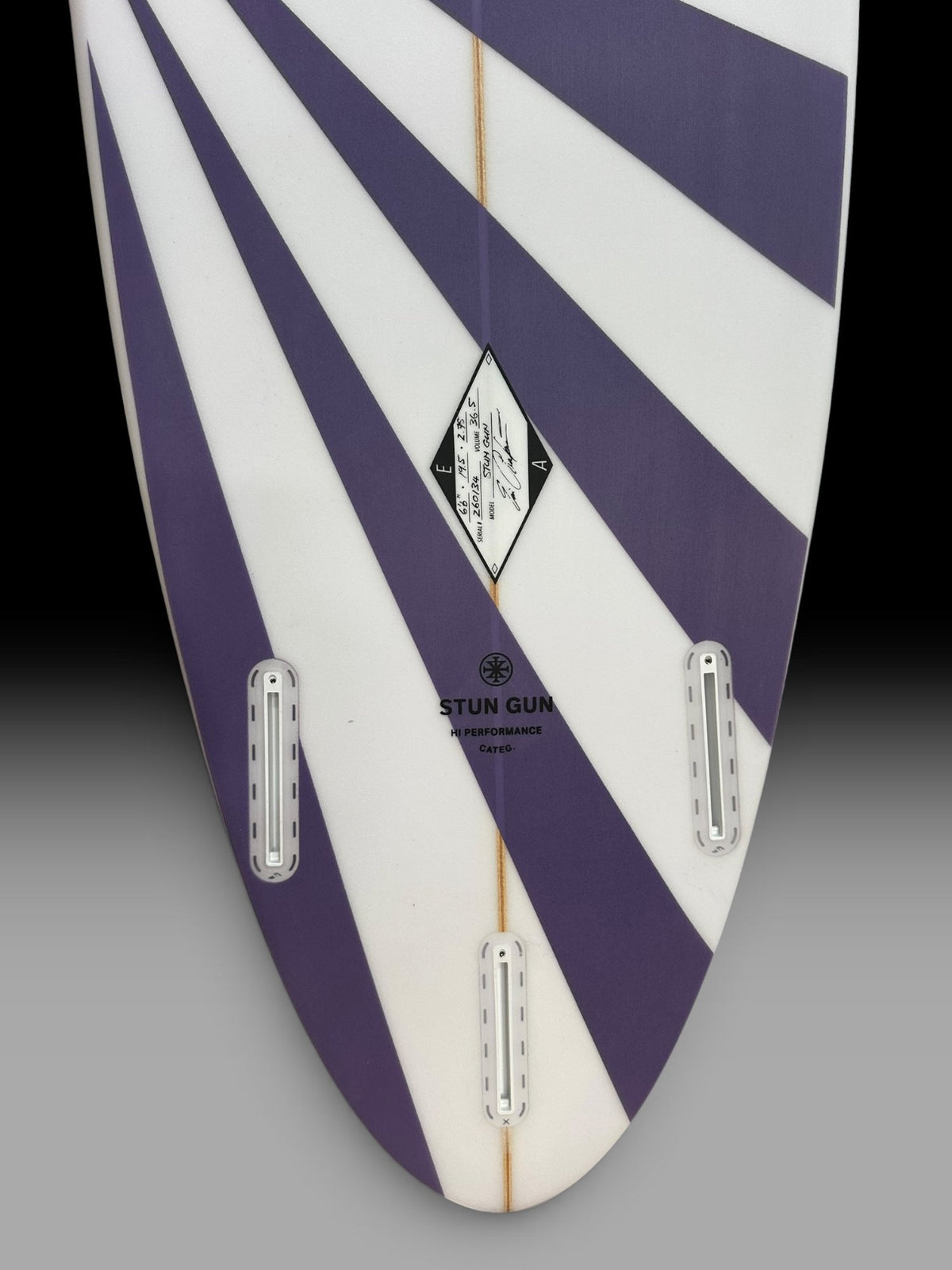 Arakawa Stun Gun 6'6 surfboard – tail and fin boxes close-up, purple sunburst spray
